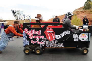 Man pushing a car with a passenger and driver inside. Man pushes person in car race_as a metaphor for UK universities becoming increasingly reliant on agents for the recruitment of European Union students.
