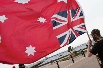 Person holding an upside down Red Ensign flag in Australia. Person holding an upside down Red Ensign flag in Australia as a metaphor that legal academics say ‘Top-down’ rules won’t solve free speech fears.