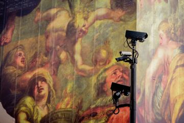 Surveillance cameras keep watch in front of a giant hoarding with classical figures in the background to illustrate report says digital surveillance of scholars ‘erodes faculty freedom’