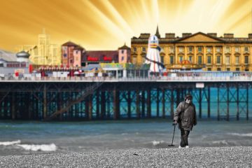 A metal detectorist searching on the shingle beach near Brighton Pier in East Sussex. A metal detectorist searching on the shingle beach near Brighton Pier in East Sussex.