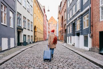 A woman walking down the street and pulling a suitcase to illustrate wanting to leave 