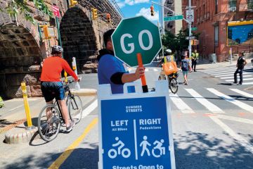 Traffic volunteer holding Go sign in Manhattan, New York City to illustrate Gates Foundation open access move ‘shifts needle in right direction’