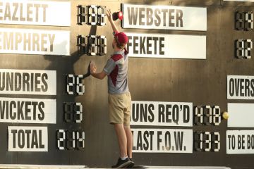 A scorer adjusts the scoreboard in Brisbane, Australia