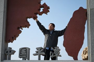 A man poses in a sculpture depicting Taiwan (R) and mainland China (L) to illustrate Cross-strait tensions hamper Chinese recruitment drive in Taiwan