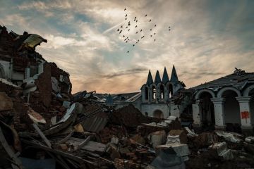 A flock of birds fly over a destroyed church at the skete of St. George’s Monastery in Dolyna, Ukraine A flock of birds fly over a destroyed church at the skete of St. George’s Monastery in Dolyna, Ukraine