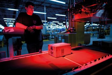 A man monitors the addressing process of a parcel inside an Amazon warehouse to illustrate Academics urge funding review after Toronto returns Amazon cash