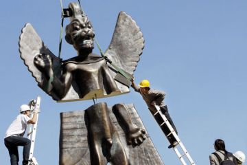 Workmen install a 6-metre fibre glass statue of the god Pazuzu onto the rooftop of the Institute of the Contemporary Arts to illustrate Science degrees ‘unwelcoming’ to religious students