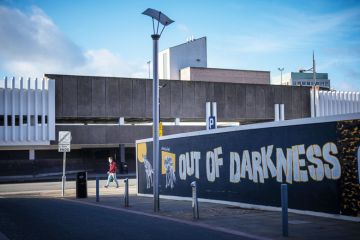  A hoarding surrounds a brownfield site waiting for redevelopment in the Horseley Fields area of Wolverhampton with graffiti reading 'Out of the darkness' to illustrate Post-92s ‘inspire and drive social mobility’