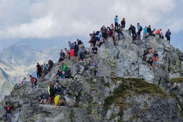 Crowd of tourists, hikers, on the narrow and rocky Rysy Peak (2500m), the highest peak in Poland to illustrate Success recast as failure 