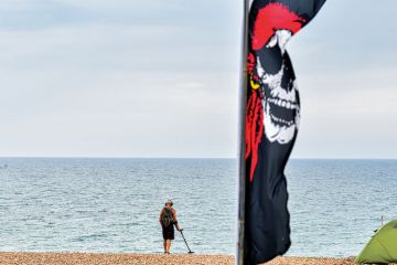 A man walks along Brighton Beach using a metal detector. A man walks along Brighton Beach using a metal detector to illustrate Programs are not detecting AI text. Is regulation needed to halt cheats?