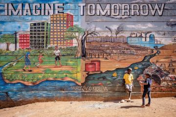 Children stand in front of a mural in Kibera slum showing an illustration of today and tomorrow Children stand in front of a mural in Kibera slum illustrating an illustration of today and tomorrow to illustrate Commonwealth can act as ‘a laboratory for change’