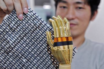 Tokyo University researcher shows a sheet containing carbon nano tubes and a robot hand Tokyo University researcher shows a sheet containing carbon nano tubes and a robot hand