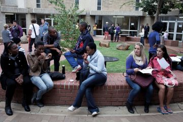 Students chat outside lecture halls at the University of the Free State in Bloemfontein, South Africa. Races are mixing more but often they socialize with their own kind.