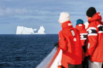 People looking at an iceberg in the distance People looking at an iceberg in the distance to illustrate Icebergs, straight ahead