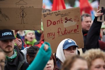 Protesters hold signs as thousands of university staff and students gather at Malieveld to protest against budget cuts on November 25, 2024 in The Hague, Netherlands to illustrate Reduced budget cuts still ‘disastrous’ for Dutch universities