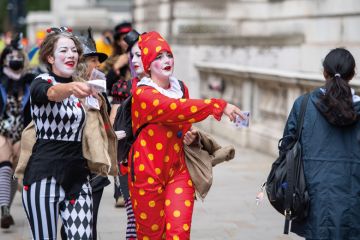 Protestors dressed as clowns hand out fake money in Westminster, London to illustrate Record £1.3 million severance pay for English sector leaders