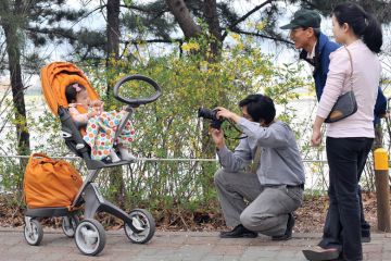 A South Korean man takes a photo of his baby sitting on a pushchair during their family picnic A South Korean man takes a photo of his baby sitting on a pushchair during their family picnic to illustrate Korean excellence plan shortlist drafted