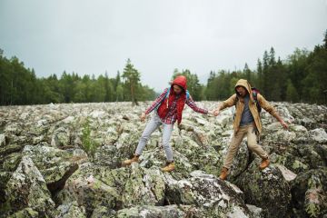 Young tourists walking down big stones while hiking Young tourists walking down big stones while hiking