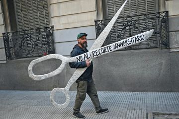 A demonstrator holds a giant scissors that read in Spanish "No to the University Cuts" A demonstrator holds a giant scissors that read in Spanish "No to the University Cuts" to illustrate Argentine academics flee Milei’s austerity crusade