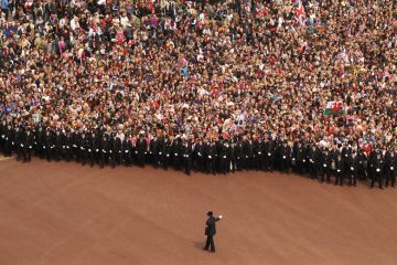 Well wishers surge along the Mall behind the police towards Buckingham Palace to celebrate the Royal Wedding of Prince William to illustrate Should student number caps be reinstated in England?