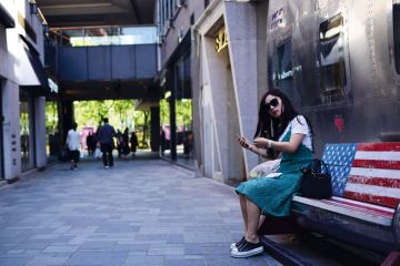 A woman sitting on an empty bench painted in a US flag in Beijing A woman sitting on an empty bench painted in a US flag in Beijing to illustrate Study abroad: US students all but absent from China