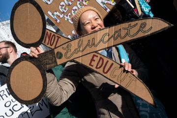 UCU member holding a cardboard banner of a pair of scissors to protest against cuts UCU member holding a cardboard banner of a pair of scissors to protest against cuts to illustrate UK sector at ‘rock bottom’ as pay dispute derails graduations