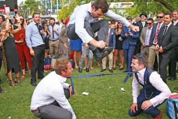  A man jumps over two men who have their ties tied together as they play a game of Limbo in Melbourne, Australia to illustrate Australian universities ‘already near’ overseas enrolment caps