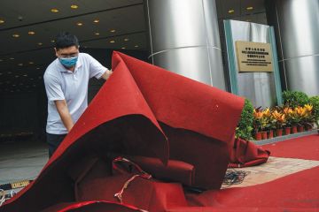 A man lifts a red carpet outside an Office A man lifts a red carpet outside an Office