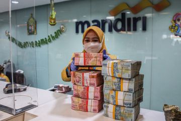 A woman arranges bundles of Indonesian rupiah banknotes at Mandiri Mikro Business Unit Bandung Braga in Bandung to illustrate South-east Asian currency slide could hit student mobility