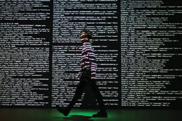 Person stands in a projection of live data feeds.