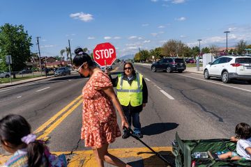 A crossing guard stops traffic as the school day ends in Cutler, California to illustrate State lawmakers launch push to end legacy admissions in US