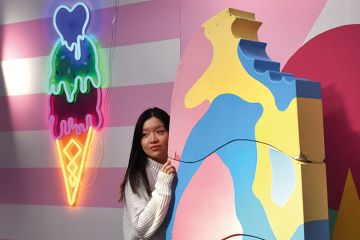 A visitor to Sugar Republic poses in front of a giant ice cream in Melbourne to illustrate ‘Sweet spot’ spending tipped for Australian budget