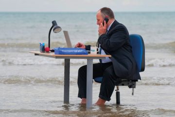 Businessman sitting at his office desk in the sea on Brighton beach Businessman sitting at his office desk in the sea on Brighton beach to illustrate Labour’s ‘right to switch off’ is ‘unfeasible’ in UK academia
