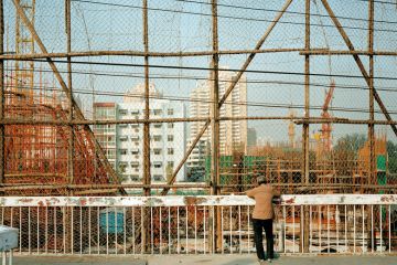 Woman looking down at a construction site, Beijing, China Woman looking down at construction site, Beijing, China to illustrate Chinese universities abandon or repurpose regional campuses