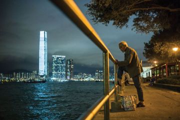 An elderly man rests his foot on a railing as he fishes in the waters of Victoria Harbour in Hong Kong An elderly man rests his foot on a railing as he fishes in the waters of Victoria Harbour in Hong Kong