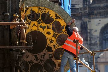 Worker removes the calendar dial of Prague's medieval astronomical clock  to illustrate Feared Czech institute takeover risks ‘incompetent interference’