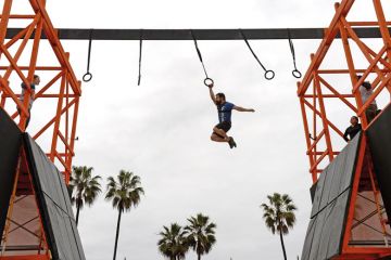 man swings across obstacle course man swings across obstacle course
