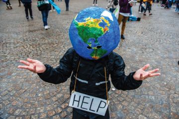 A man with an earth ball on his head and help sign makes hand gesture A man with an earth ball on his head and help sign makes hand gesture