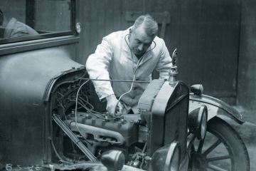 A motor mechanic listens to a car engine with a stethoscope.