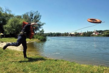 A rescuer throws a lifebelt into a lake A rescuer throws a lifebelt into a lake