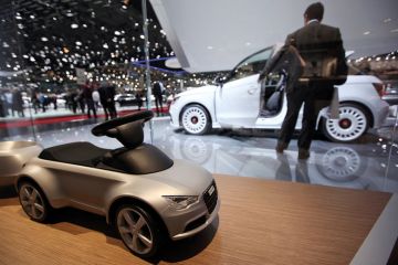 A toy car for Audi AG is seen on the company's stand with a man looking at white car in background A toy car for Audi AG is seen on the company's stand with a man looking at white car in background