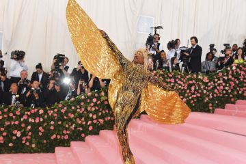 on the red carpet person wearing huge gold sparkle angel wings on the red carpet person wearing huge gold sparkle angel wings