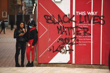 two people stand stand beside Black Lives Matters graffiti two people stand stand beside Black Lives Matters graffiti