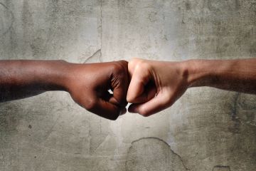 Black and white hands touch knuckles