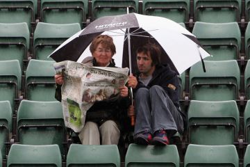 Woman and man read paper in rain Woman and man read paper in rain