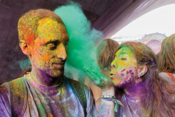 Woman blowing colour into male friend's face