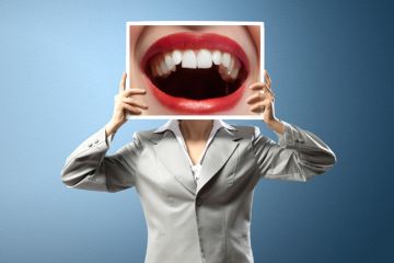 Woman holding photo of open mouth over face Woman holding photo of open mouth over face
