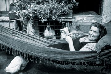 Woman lying in hammock reading book