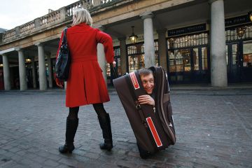 woman pulling along man hidden in suitcase woman pulling along man hidden in suitcase