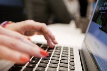 Woman typing Apple MacBook laptop